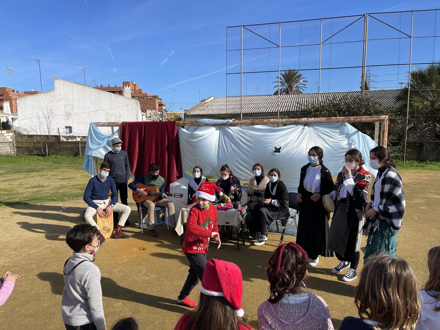 Representación navideña al aire libre en el patio, con público de pie alrededor