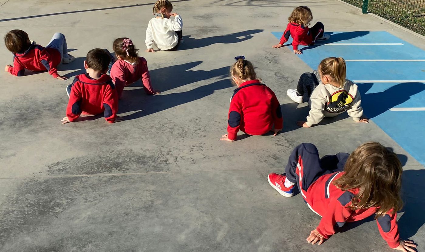 Niños de Infantil jugando a gatas sobre el suelo pintado del patio