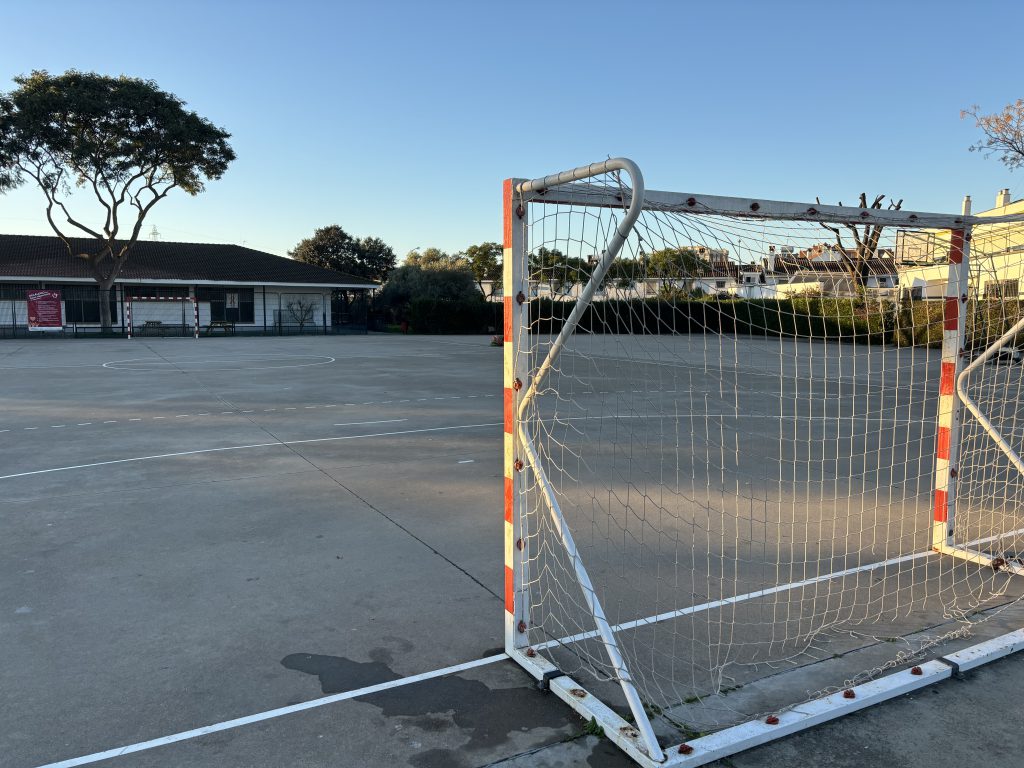 Portería de fútbol sala en la pista exterior, con el edificio de aulas al fondo