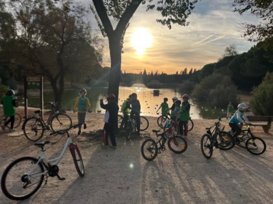 Grupo de alumnos con sus bicicletas junto al río, a contraluz del atardecer