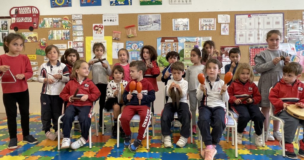 Grupo de Infantil sentado en sillas sobre la alfombra, con material en las manos