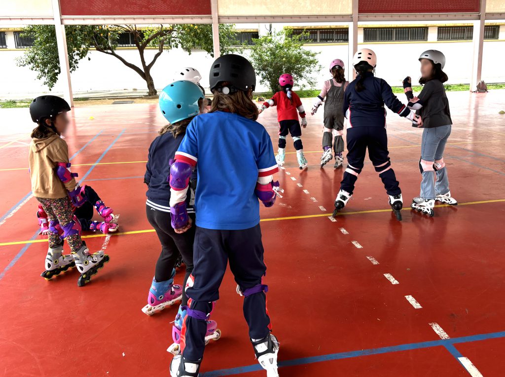 Grupo de alumnas patinando con casco y protecciones en la pista cubierta